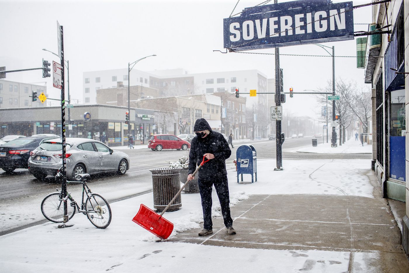 Tom Foran shovels snow as a wintry mix falls in Chicago's Edgewater neighborhood March 15, 2021. Chicago was set to get hit by "briefly heavy" snow late Monday morning and into the afternoon, before some drizzling and light snow in the early evening, according to the National Weather Service's Chicago-area office.